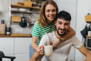 Young couple in the kitchen looking at the camera