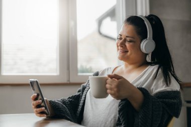 beautiful woman with smartphone listening to music and having coffee
