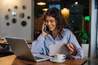 Young business woman is having a phone call in a cafe