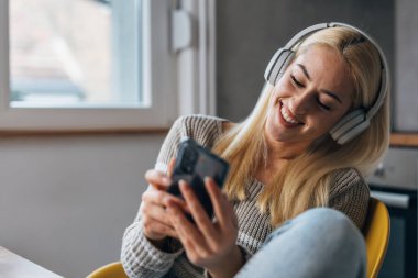 Beautiful caucasian woman with headphones looks at her phone