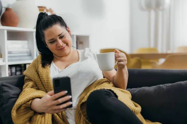 Overweight woman is relaxing on the sofa at home
