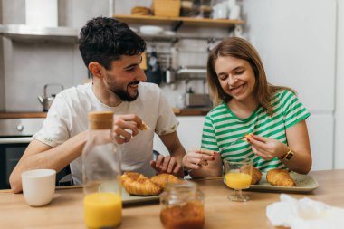A young couple eats croissants for breakfast
