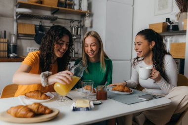 Three happy friends have breakfast together