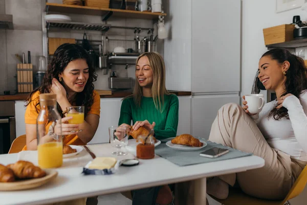 Three female friends are talking in the kitchen