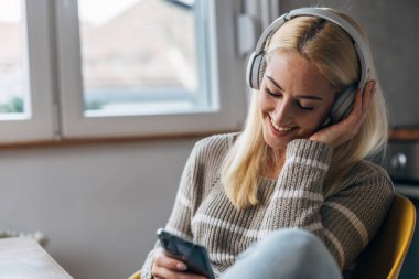 Blonde woman enjoys listening music on headphones