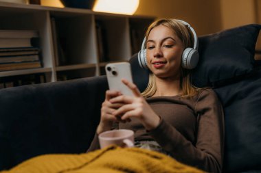 Blond Caucasian woman uses her phone at home