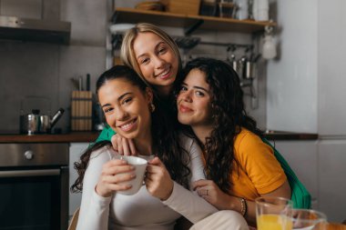 Front view of three beautiful female friends hugging