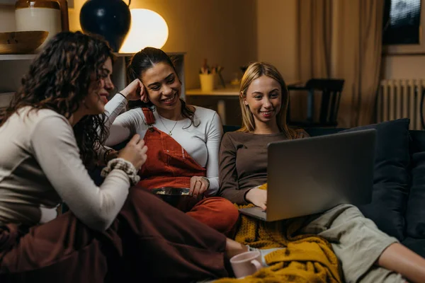 Three female friends are watching a movie on laptop