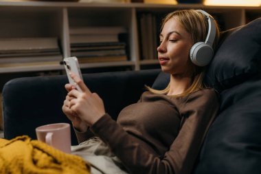 A young blond woman rests at home on the sofa