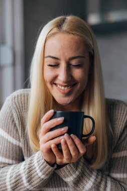 Beautiful blond woman enjoys a hot beverage