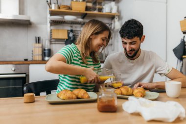 Woman pours orange juice for her boyfriend