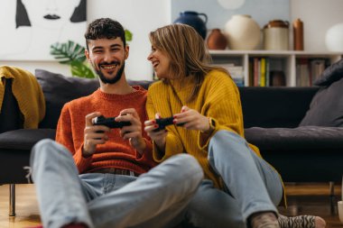 Joyful woman and man are playing video games at home