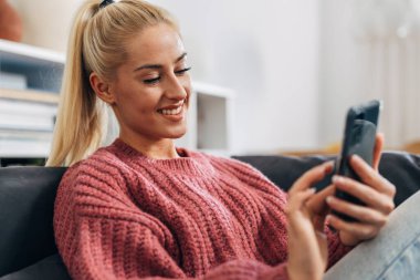 Close up view of a beautiful woman using her mobile phone at home