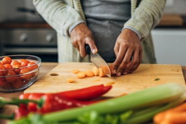 Close up view of woman hands cutting carrot