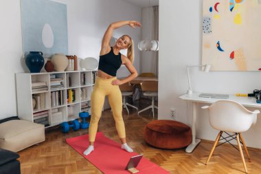 Caucasian woman is warming up before exercising at home