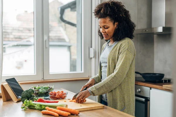 stock image Side view of an African American woman cutting vegetables for salad