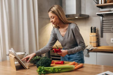 Woman is reading a recipe from the recipe book