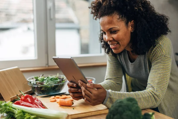 stock image Happy woman looks at a recipe in the kitchen