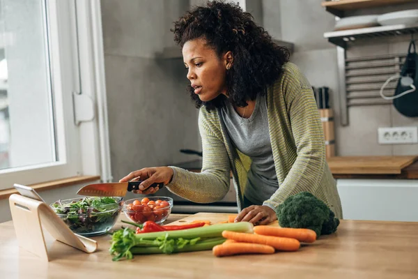 stock image A mixed race woman is checking the recipe for a vegan meal