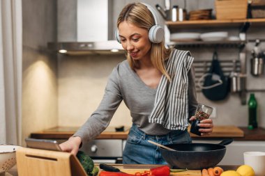 Mutlu kadın mutfakta yemek pişirir ve müzik dinler.