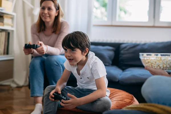 A young boy plays video games with his mother