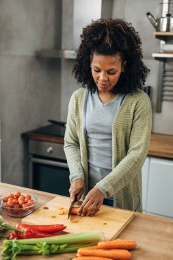 Kadın mutfakta sebze kesiyor.