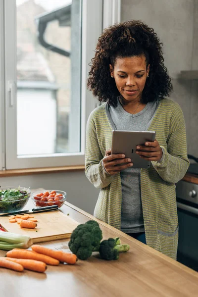 stock image A mixed race woman is using tablet in the kitchen