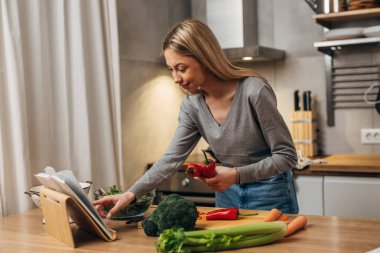 Güzel sarışın bir kadın mutfakta yemek pişiriyor.