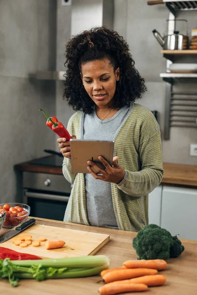 stock image A middle aged woman is cooking in the kitchen and holding a tablet