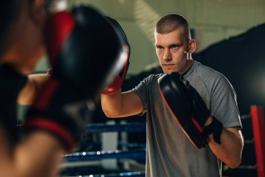 Antrenör saldırma tekniklerini öğretirken pedleri tutuyor.