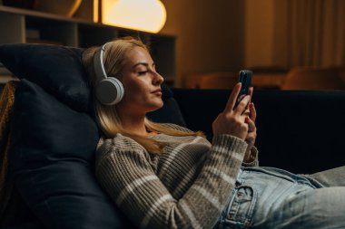 Bir kadın akşamleyin kanepede dinleniyor.