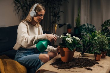 Mutlu genç kadın evinin bitkilerini yıkıyor.