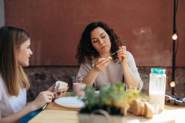 Anne ve kızı arka bahçedeki masaya oturur ve kahvaltı ederler.
