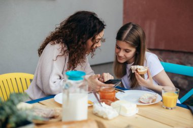 Anne ve kızı hafta sonları kahvaltıda arka bahçede kaynaşırlar.