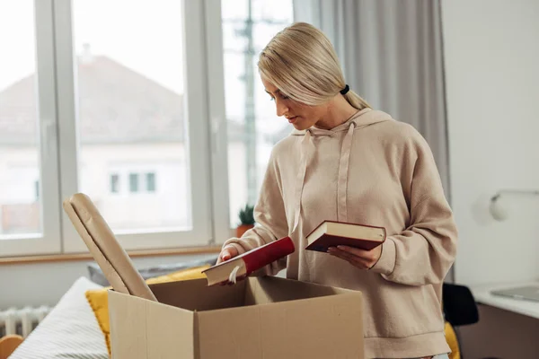一个金发白人女人正在从流动的盒子里打开她的书 — 图库照片