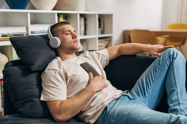 一个男人在沙发上休息 他在听音乐的时候睡着了 — 图库照片