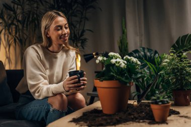 Kafkasyalı mutlu bir kadın ev bitkilerine gururla bakıyor.