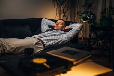 Çok çalışan adam evde müzikle rahatlar.