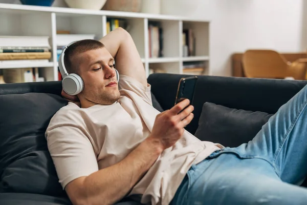 Caucasian Man Uses His Mart Phone Lays Sofa — Stock Photo, Image