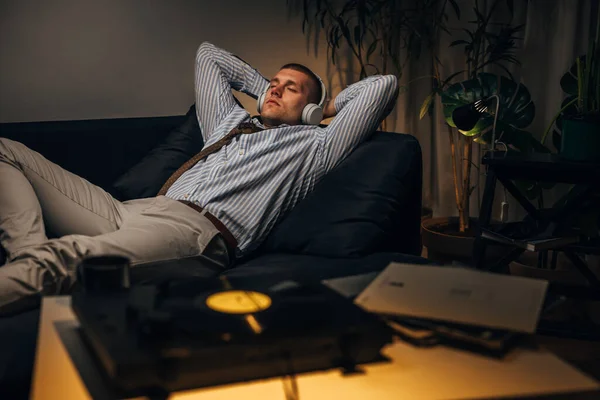 A young businessman is resting at home with music after a hard day at work