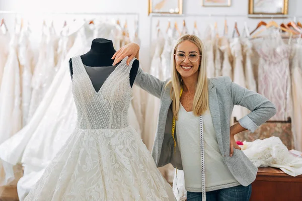 Tailor stands proudly next to a wedding dress she created