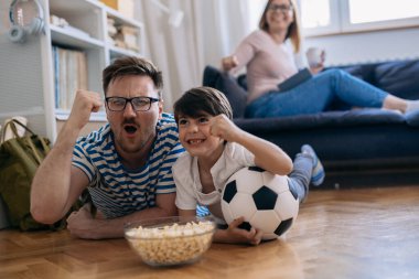 Mutlu futbol taraftarları maçı izlerken tezahürat yapıyorlar. Aile zamanı.