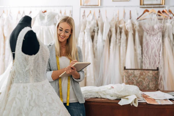 Tailor in a wedding dress salon is working on a new dress
