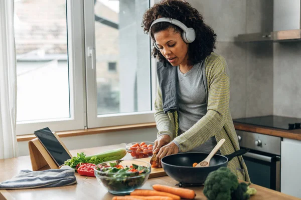 stock image A multiracial woman with headphones is cooking in the kitchen