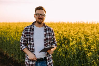 Beyaz adamın portresi. Gözlüklü. Yağ çekirdeği tecavüz tarlasının yanında duruyor..