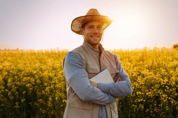 Portrait of a handsome Caucasian farmer standing in the field at sunset