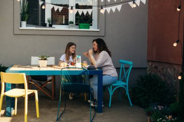 Anne ve genç kız evlerinin dışında yemek yiyorlar. 