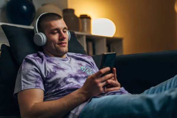 Ein Kaukasischer Mann Mit Kopfhörern Sitzt Auf Dem Sofa Und — Stockfoto