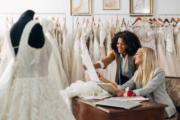 Two beautiful women work together in a bridal salon as designers.