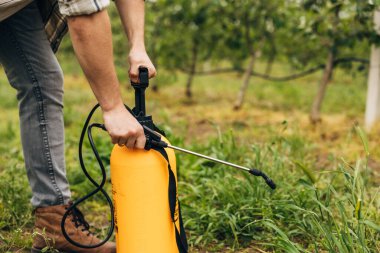 Bahçesini korumak için bir şişe kimyasal kullanan bir adamın yakın plan görüntüsü.